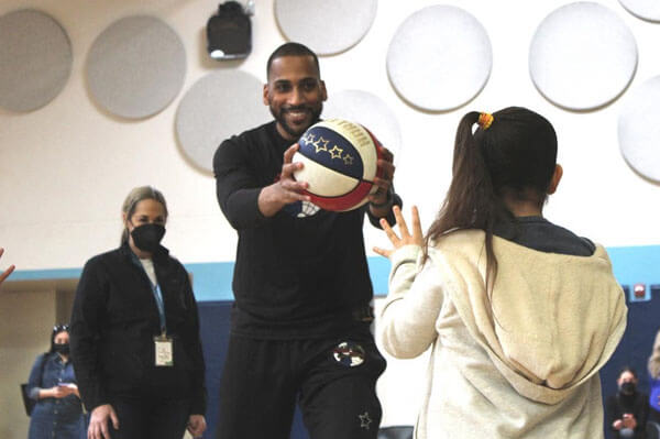 Zeus McClurkin of The Original Harlem Globetrotters throws basketball to student